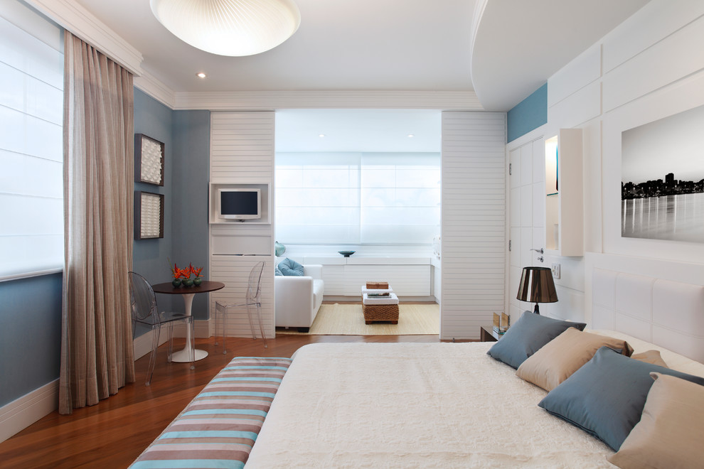 Ejemplo de dormitorio principal y televisión contemporáneo con paredes azules y suelo de madera en tonos medios