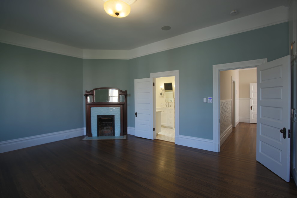 Foto di una grande camera matrimoniale american style con pareti blu, parquet scuro, cornice del camino in legno e camino ad angolo