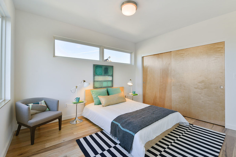 Imagen de habitación de invitados moderna grande con paredes blancas y suelo de madera clara