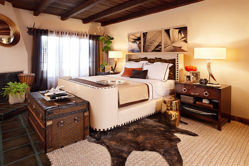 Diseño de dormitorio principal rústico grande con paredes beige, suelo de baldosas de terracota, chimenea de esquina, marco de chimenea de yeso y suelo marrón