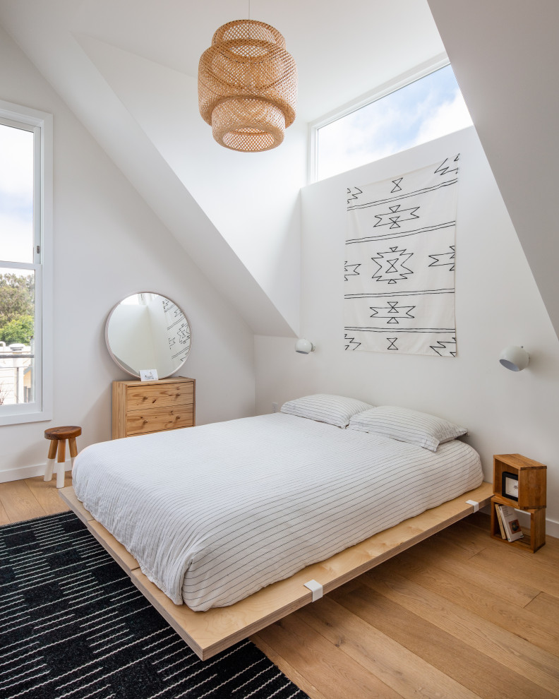 Modelo de dormitorio nórdico con paredes blancas, suelo de madera en tonos medios y suelo marrón