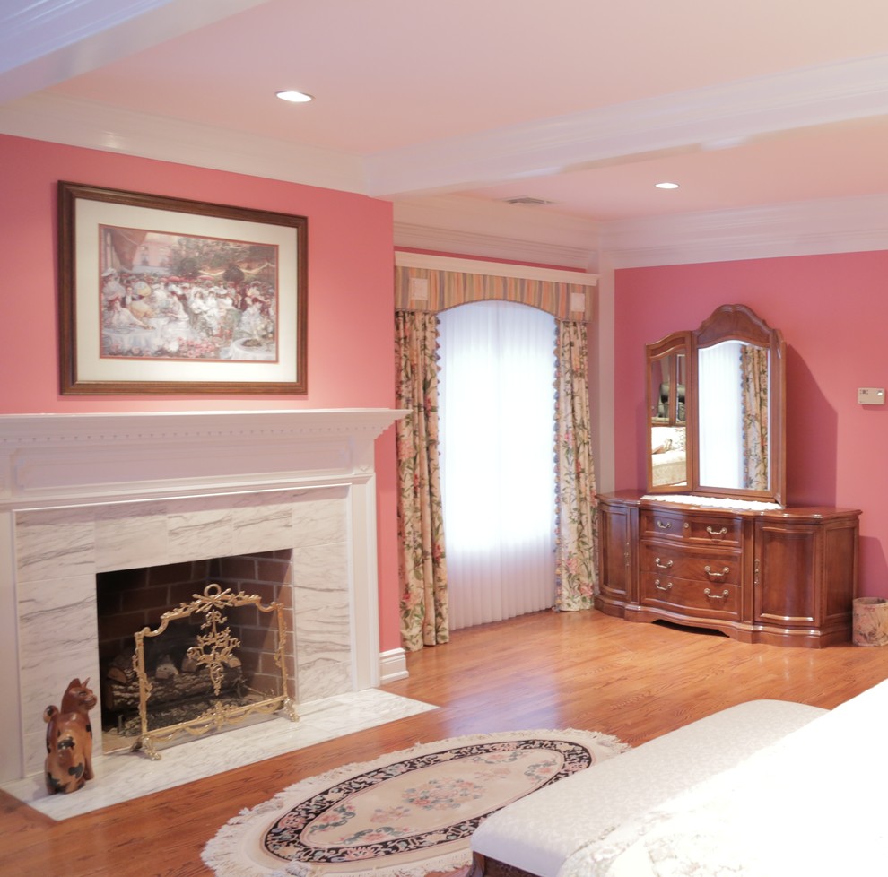 Idée de décoration pour une grande chambre parentale tradition avec un mur rose, un sol en bois brun, une cheminée standard, un manteau de cheminée en carrelage et un sol marron.
