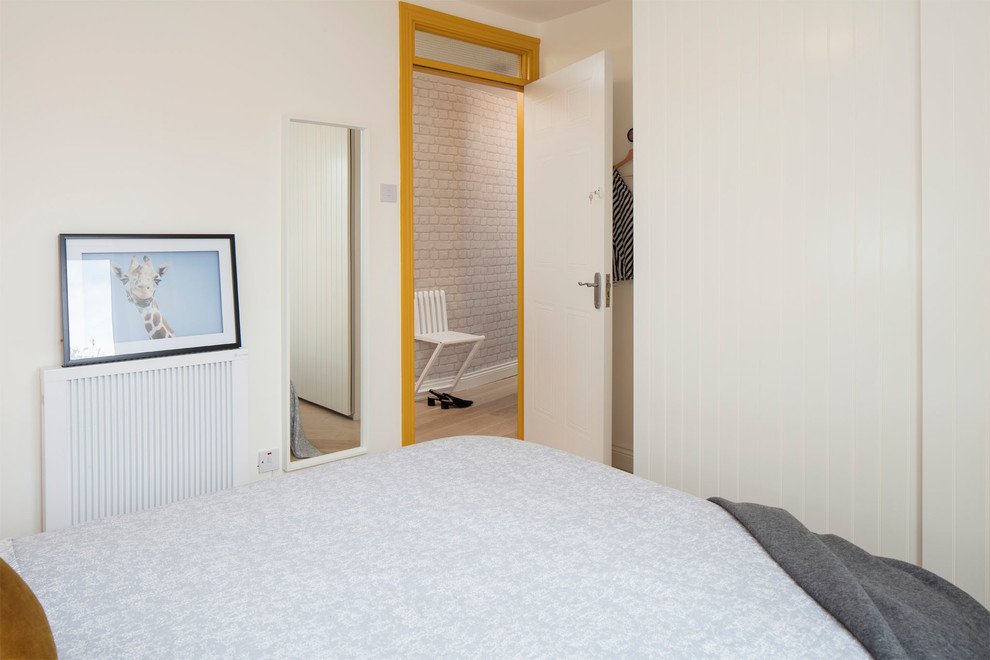 Immagine di una piccola camera matrimoniale nordica con pareti bianche, pavimento in legno massello medio e pavimento beige