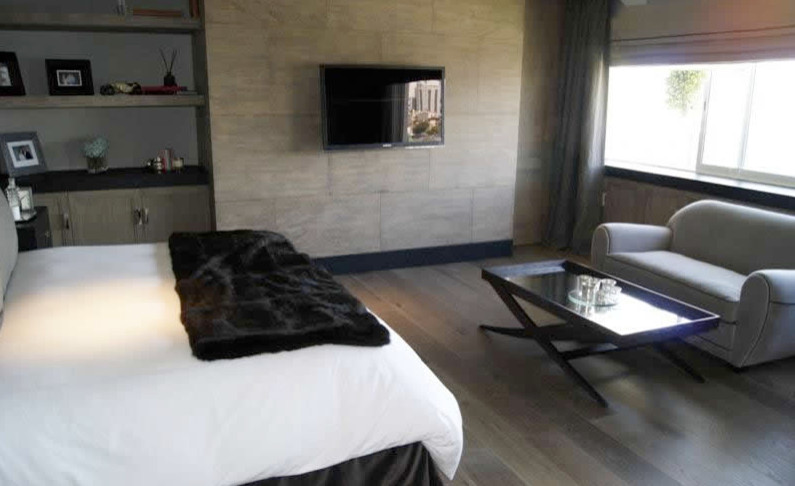 Modelo de dormitorio principal clásico grande sin chimenea con paredes beige y suelo de madera en tonos medios