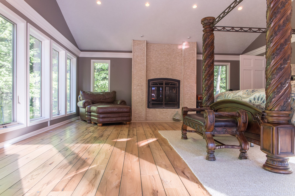 Inspiration for a large traditional master bedroom in Boston with light hardwood flooring, brown walls, a standard fireplace, a metal fireplace surround and brown floors.