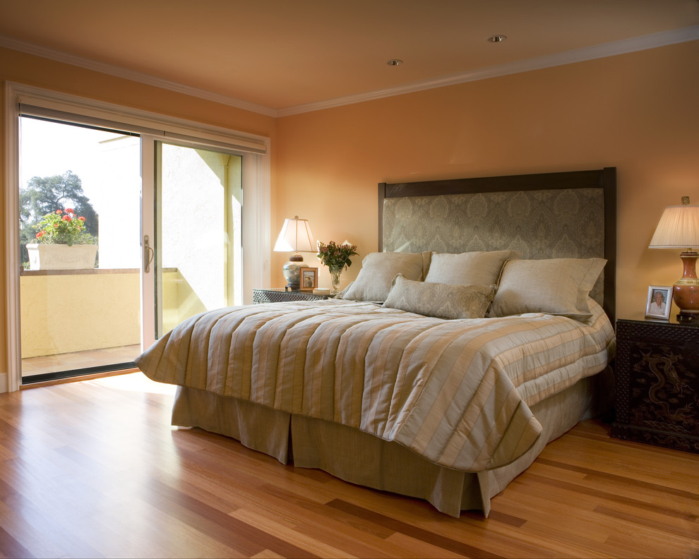 Imagen de dormitorio principal actual sin chimenea con parades naranjas, suelo de madera en tonos medios y suelo naranja