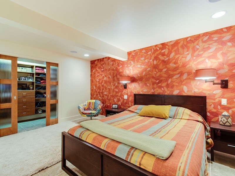 Ispirazione per una camera da letto design con pareti arancioni