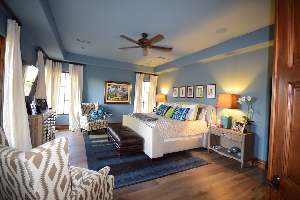 Imagen de dormitorio principal actual de tamaño medio sin chimenea con paredes azules, suelo de madera en tonos medios y suelo marrón