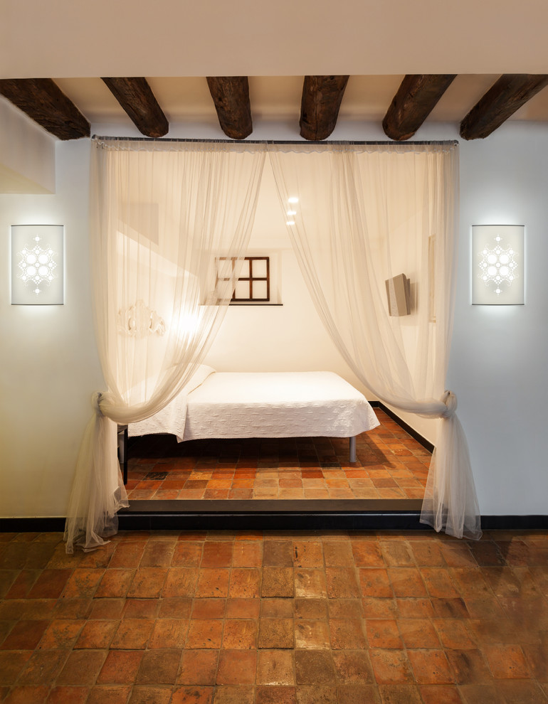 На фото: маленькая гостевая спальня (комната для гостей) в стиле фьюжн с белыми стенами и полом из терракотовой плитки для на участке и в саду с