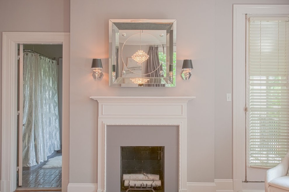 Cette photo montre une grande chambre parentale tendance avec un mur violet, un sol en bois brun, une cheminée standard et un manteau de cheminée en plâtre.