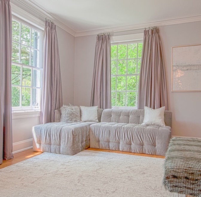 Cette image montre une grande chambre parentale design avec un mur violet, un sol en bois brun, une cheminée standard et un manteau de cheminée en plâtre.