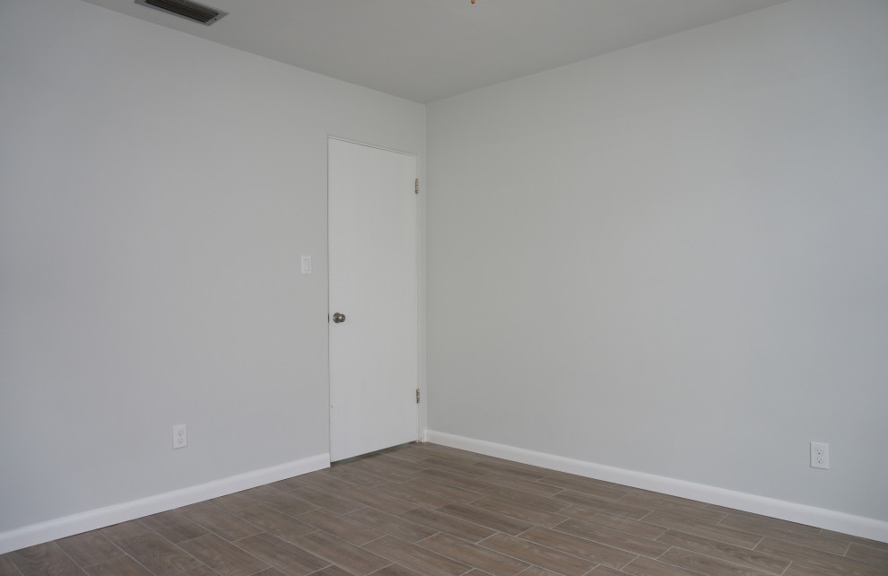 Immagine di una piccola camera da letto moderna con pareti grigie, pavimento in gres porcellanato e pavimento marrone
