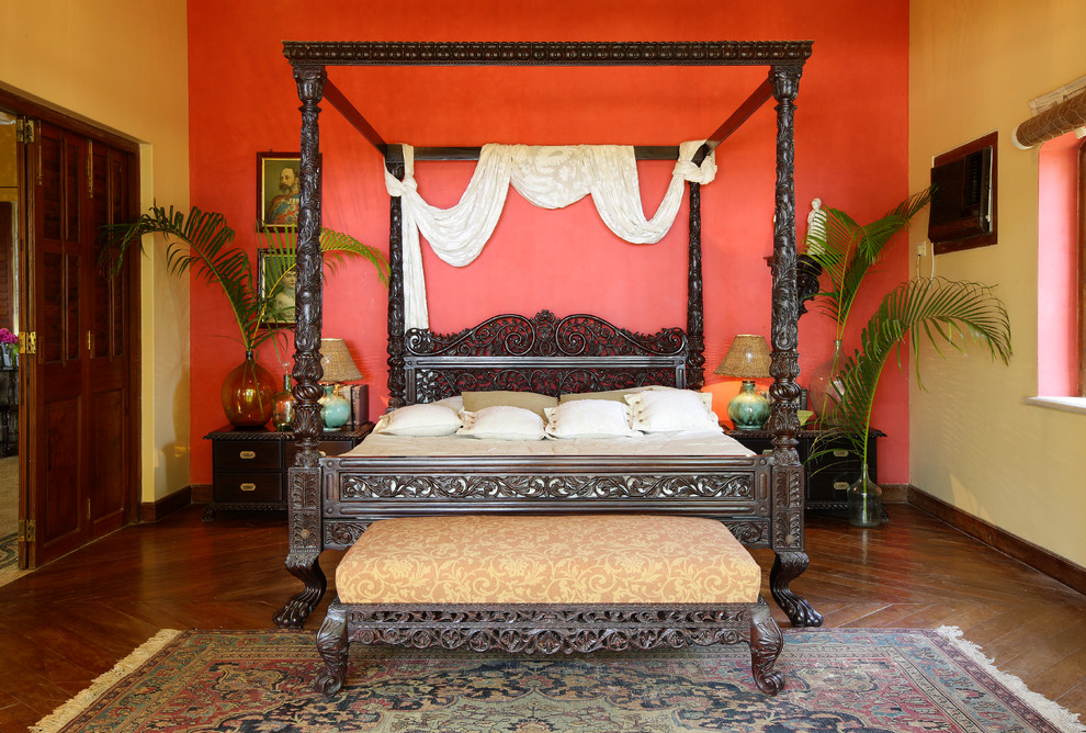 Hauptschlafzimmer ohne Kamin mit roter Wandfarbe und dunklem Holzboden in Mumbai