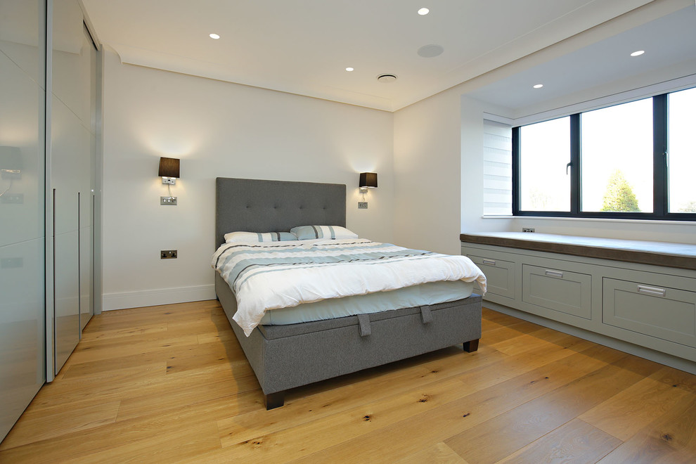 Bedroom - large modern guest medium tone wood floor and brown floor bedroom idea in London with beige walls