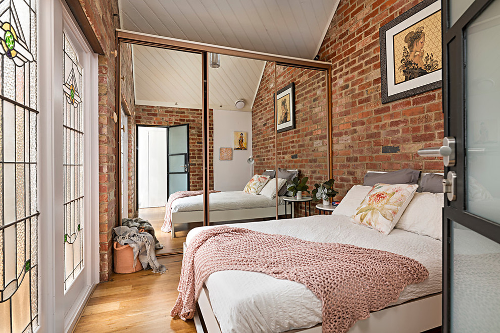 Ejemplo de dormitorio principal minimalista de tamaño medio sin chimenea con paredes rojas, suelo de madera en tonos medios y suelo marrón