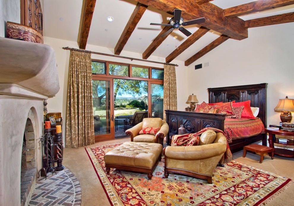 Photo of a mediterranean master bedroom in San Diego with white walls, carpet and a standard fireplace.