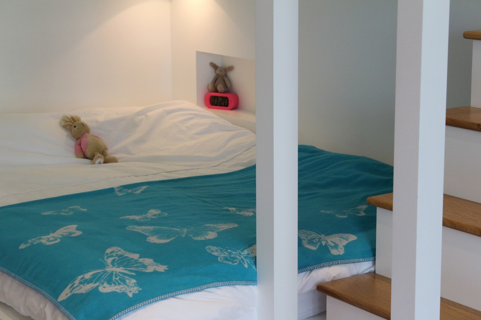 This is an example of a medium sized nautical guest bedroom in West Midlands with white walls and light hardwood flooring.
