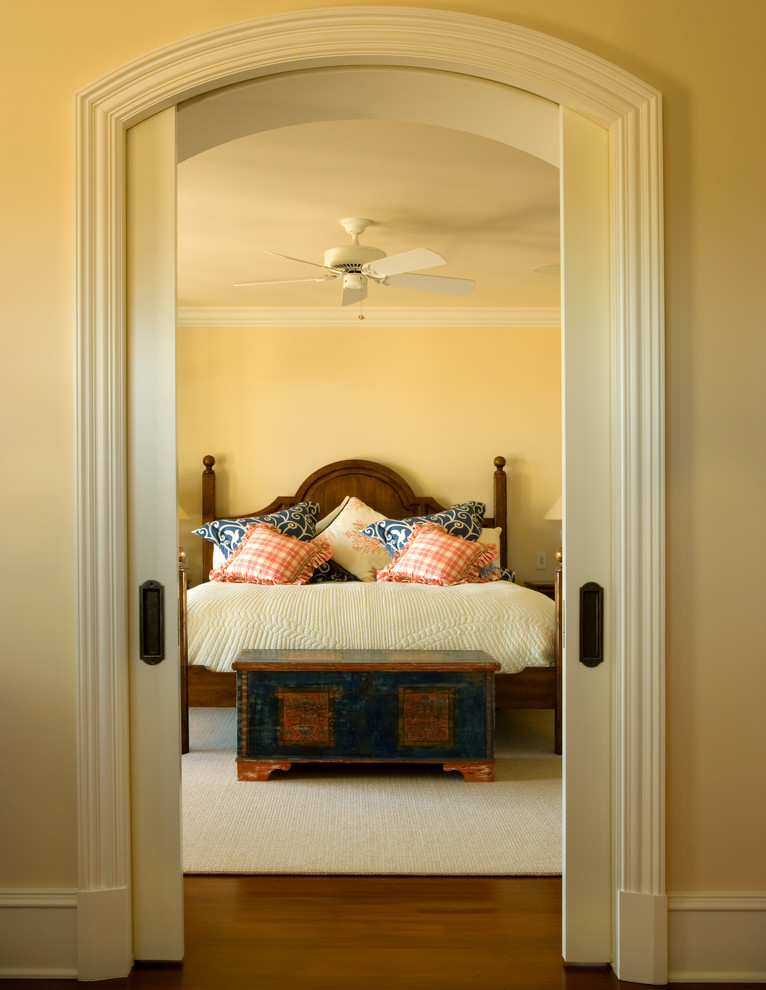 Mittelgroßes Klassisches Hauptschlafzimmer ohne Kamin mit gelber Wandfarbe und braunem Holzboden in Charleston