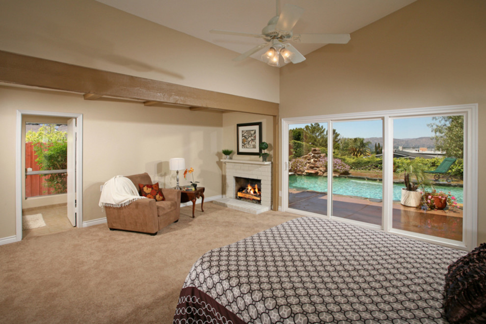 Large island style master carpeted bedroom photo in Austin with beige walls, a standard fireplace and a brick fireplace