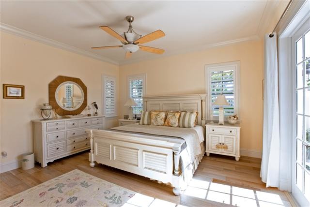 Inspiration for a large coastal master bedroom in Miami with no fireplace, beige walls and light hardwood flooring.