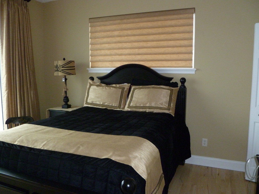 Imagen de dormitorio principal clásico de tamaño medio sin chimenea con paredes beige y suelo de madera clara