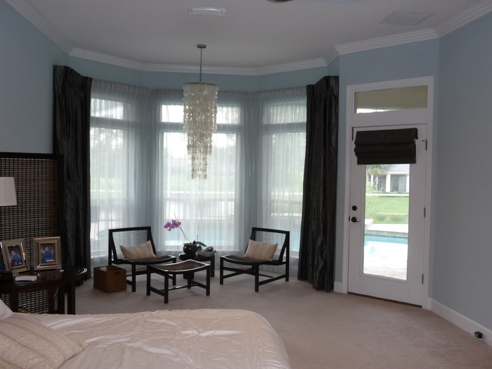 This is an example of a large world-inspired master bedroom in Jacksonville with blue walls, carpet and no fireplace.