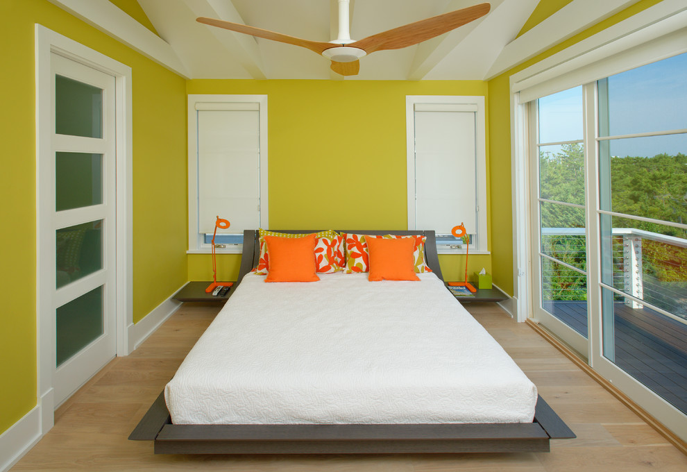 Foto på ett funkis sovrum, med gula väggar och ljust trägolv