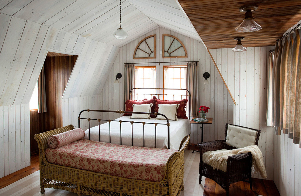 На фото: спальня на мансарде в стиле кантри с белыми стенами и темным паркетным полом с