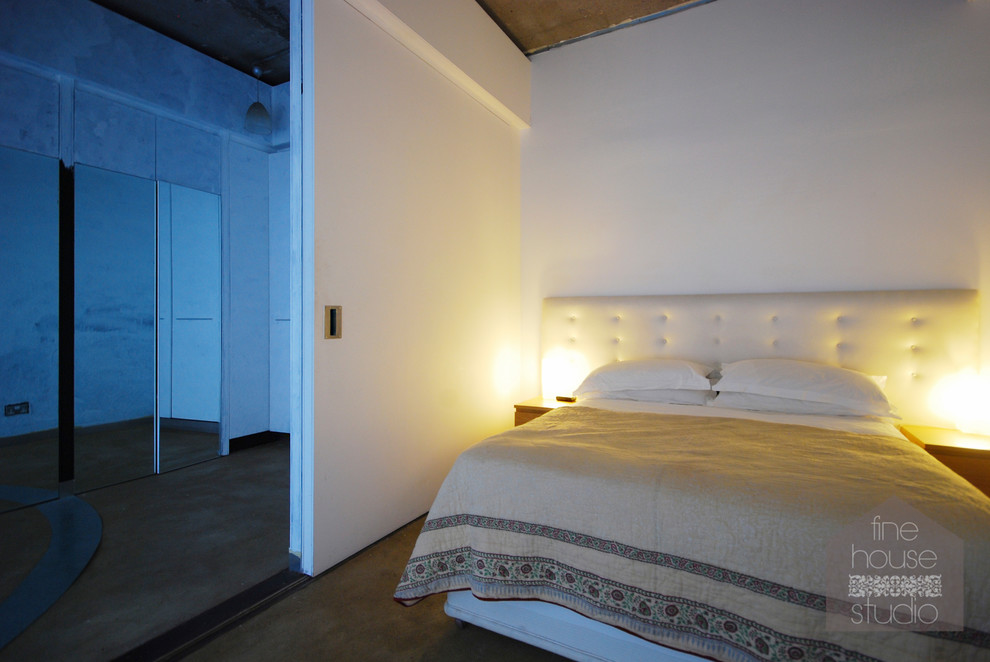 Großes Modernes Schlafzimmer im Loft-Style mit weißer Wandfarbe und Betonboden in Gloucestershire