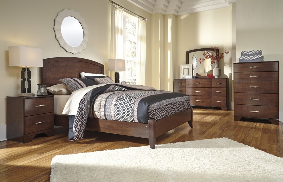 Modelo de dormitorio sin chimenea con paredes beige y suelo de madera en tonos medios