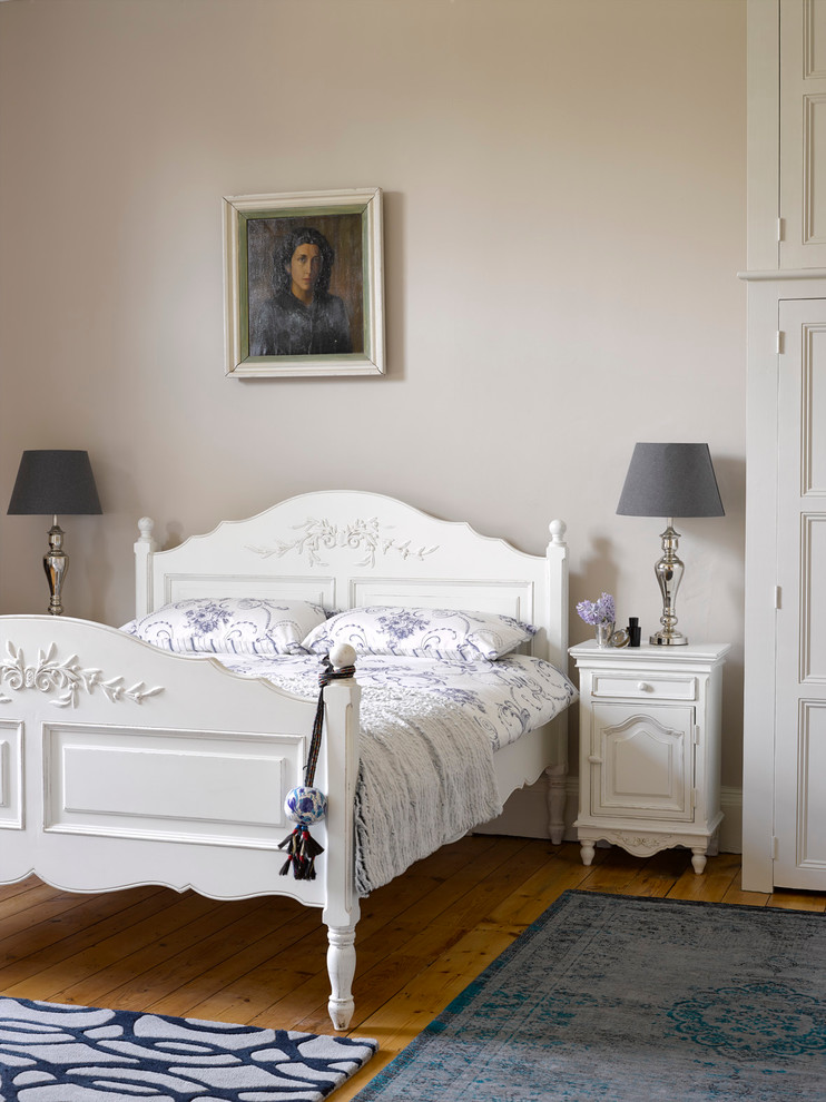 Ornate medium tone wood floor bedroom photo in Hertfordshire with beige walls