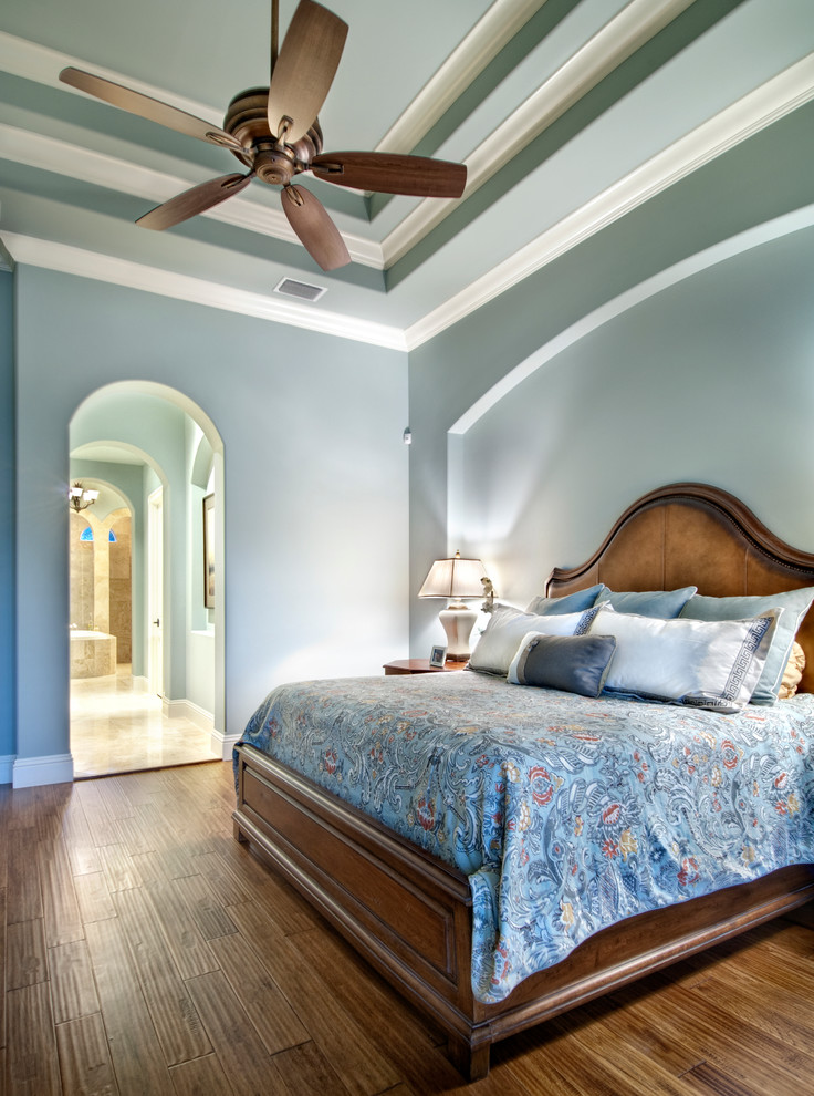 Immagine di una camera matrimoniale chic con pareti blu e pavimento in legno massello medio