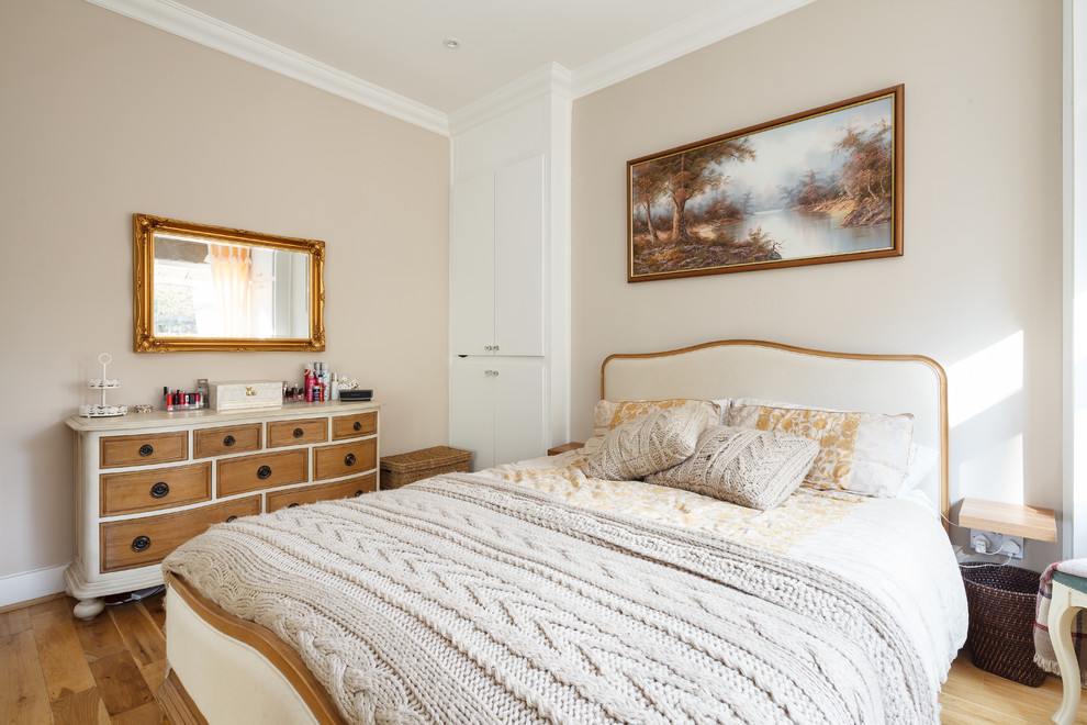 This is an example of a classic bedroom in Manchester with beige walls, medium hardwood flooring and brown floors.