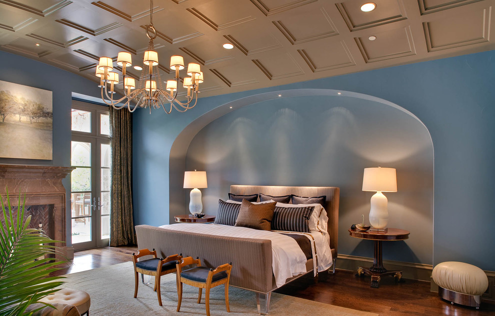 На фото: спальня в средиземноморском стиле с синими стенами, паркетным полом среднего тона, стандартным камином, фасадом камина из камня и кроватью в нише