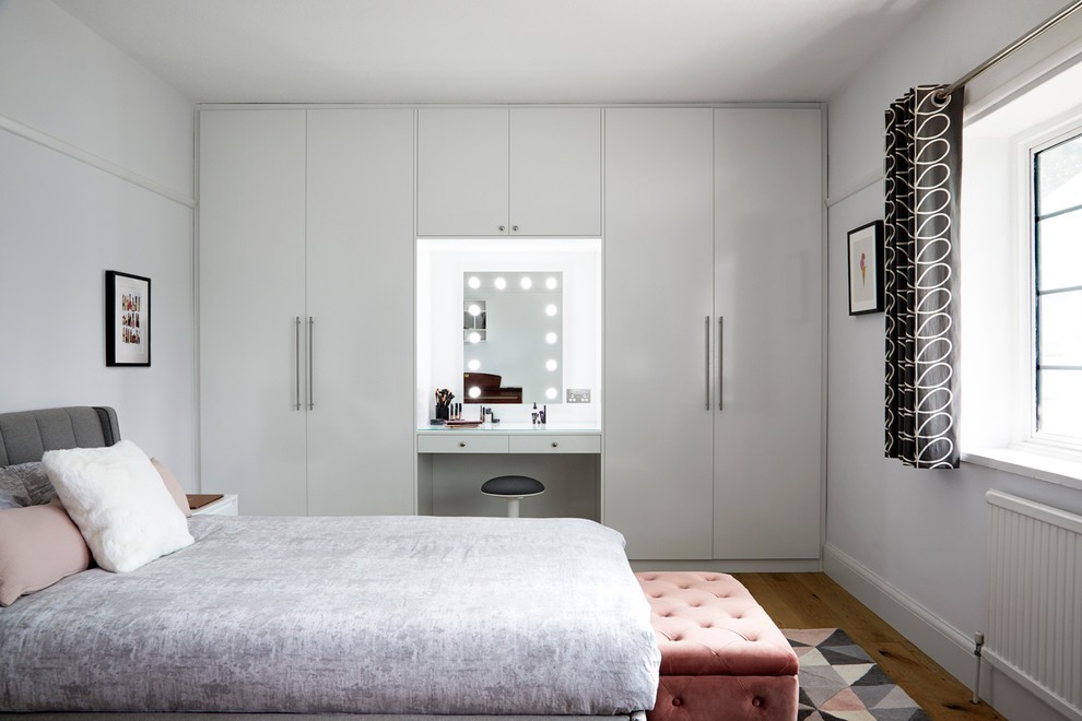 Design ideas for a scandinavian grey and pink bedroom in Surrey with white walls, light hardwood flooring and no fireplace.