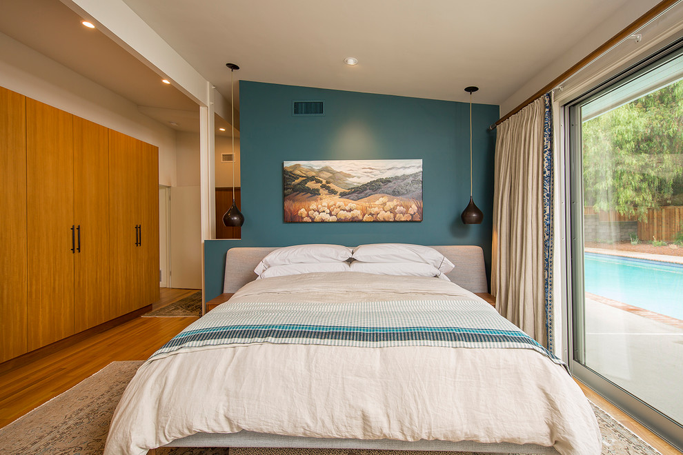 Ejemplo de dormitorio retro con paredes azules, suelo de madera en tonos medios y suelo marrón