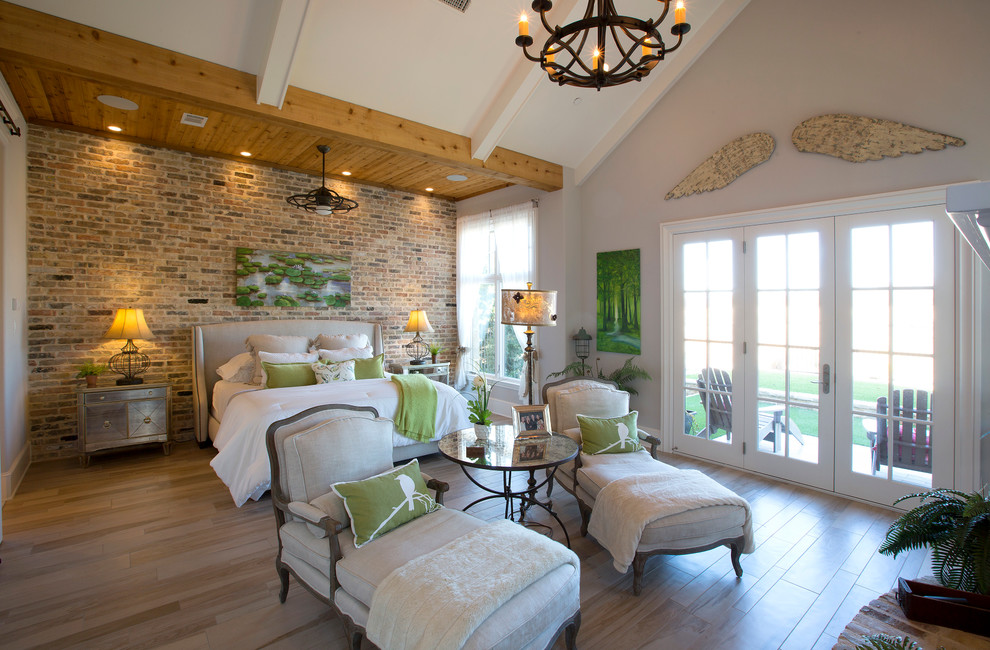 Großes Country Hauptschlafzimmer mit grauer Wandfarbe, hellem Holzboden, Kamin, Kaminumrandung aus Backstein und braunem Boden in Dallas