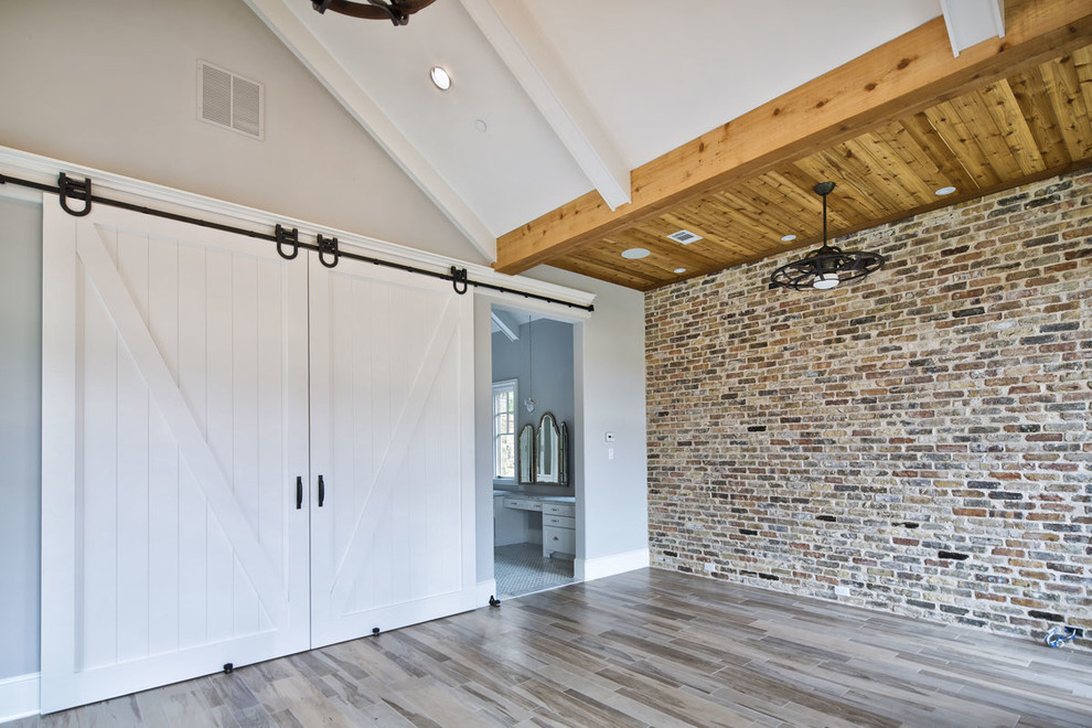 Idéer för stora funkis huvudsovrum, med grå väggar, ljust trägolv, en standard öppen spis och en spiselkrans i tegelsten