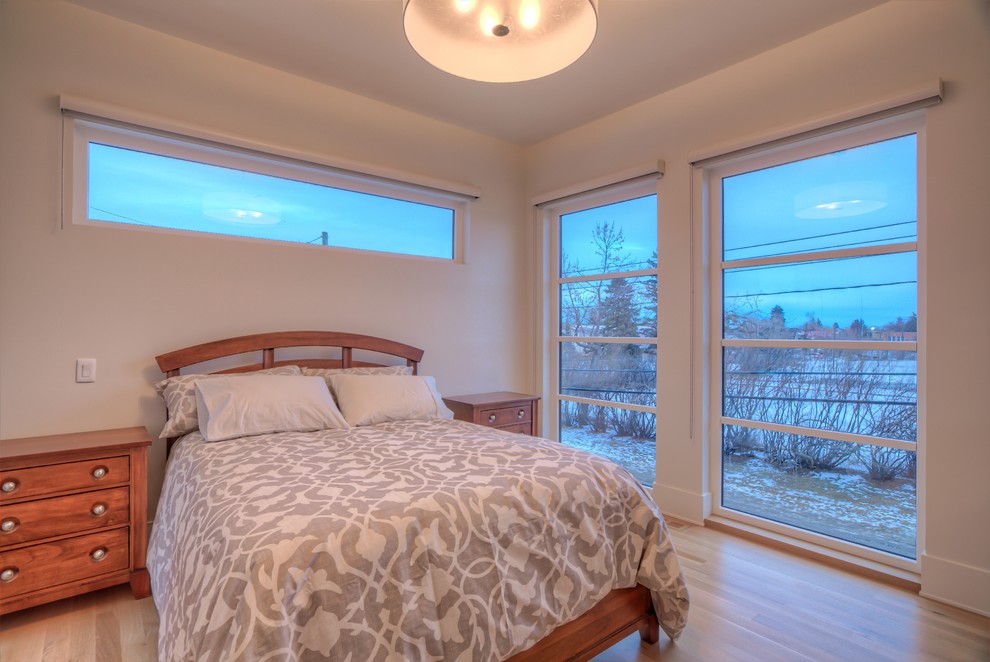 Photo of a modern master bedroom in Calgary with white walls and light hardwood flooring.