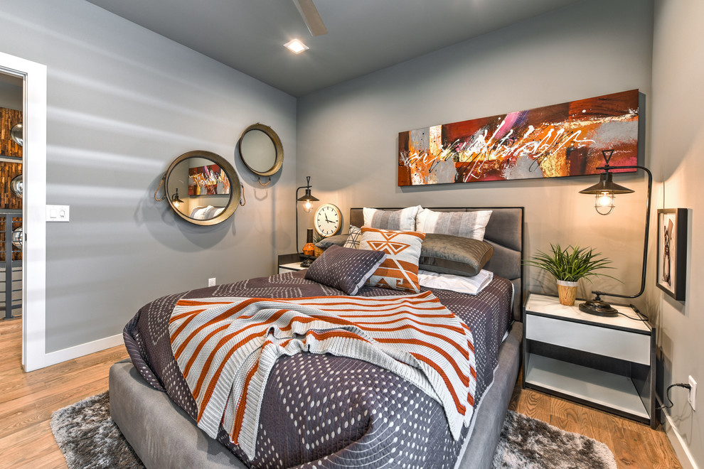 Immagine di una piccola camera degli ospiti minimalista con pareti grigie e pavimento in legno massello medio