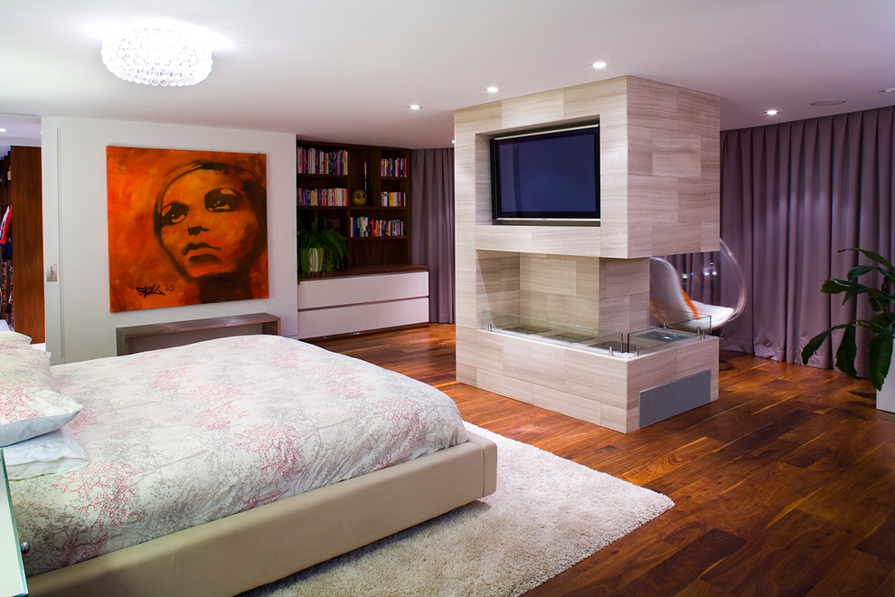 Foto de dormitorio principal contemporáneo con suelo de madera en tonos medios y chimenea de doble cara