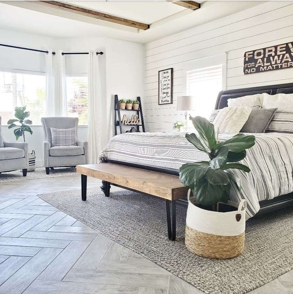 Farmhouse master bedroom in Las Vegas with white walls, ceramic flooring, a standard fireplace, a timber clad chimney breast, grey floors, exposed beams and tongue and groove walls.