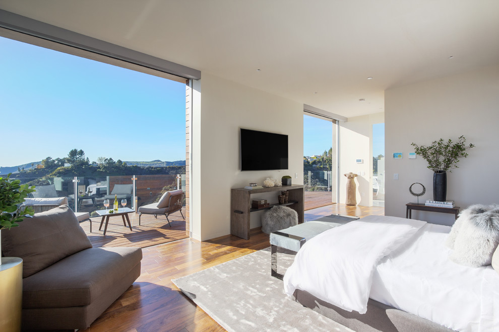 Großes Modernes Hauptschlafzimmer ohne Kamin mit weißer Wandfarbe und braunem Holzboden in Los Angeles