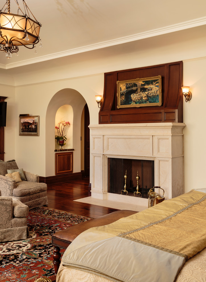 Example of a huge tuscan master dark wood floor bedroom design in Los Angeles with beige walls, a standard fireplace and a stone fireplace