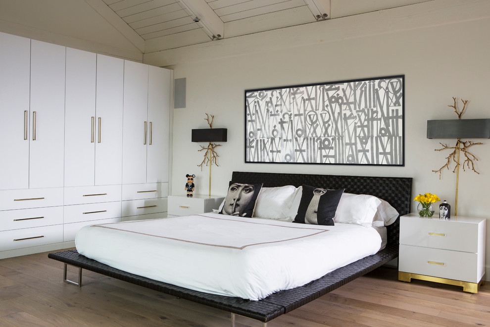 Imagen de dormitorio principal costero grande sin chimenea con paredes blancas y suelo de madera clara