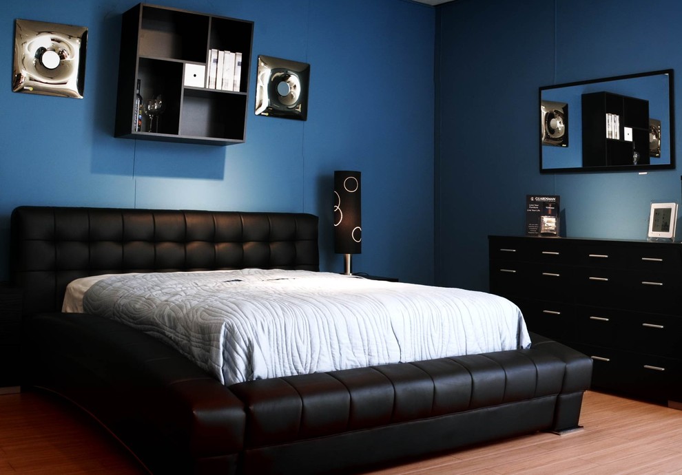 This is an example of a medium sized contemporary bedroom in Houston with blue walls and light hardwood flooring.