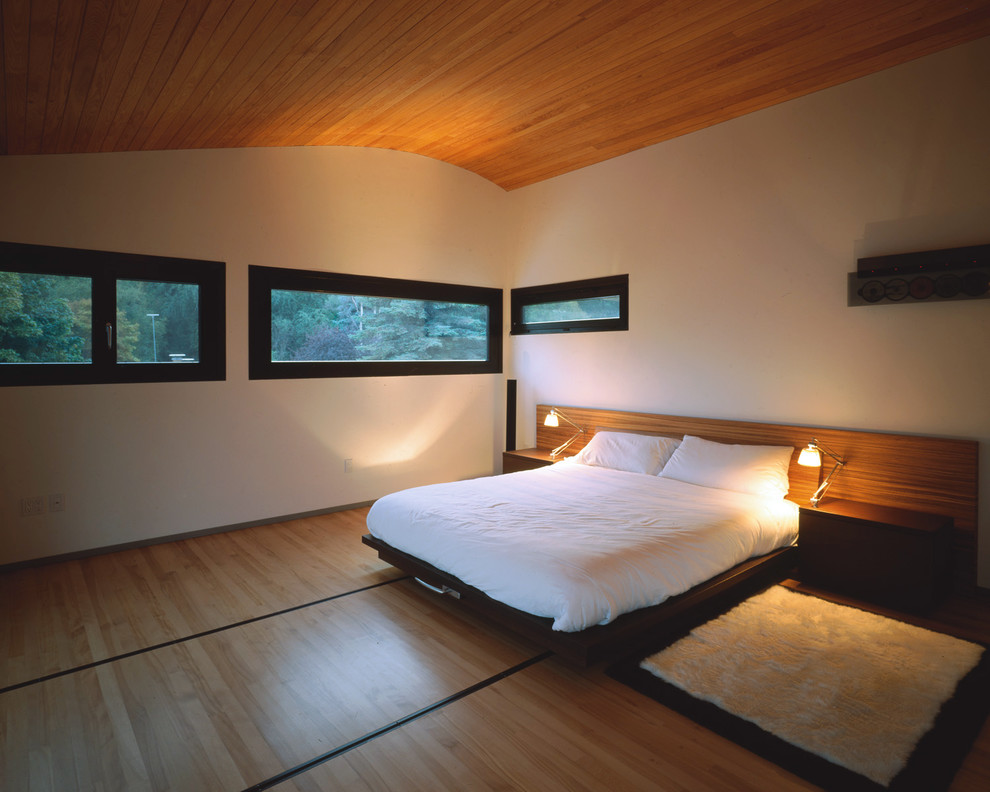 Modern inredning av ett mellanstort huvudsovrum, med beige väggar, ljust trägolv och beiget golv