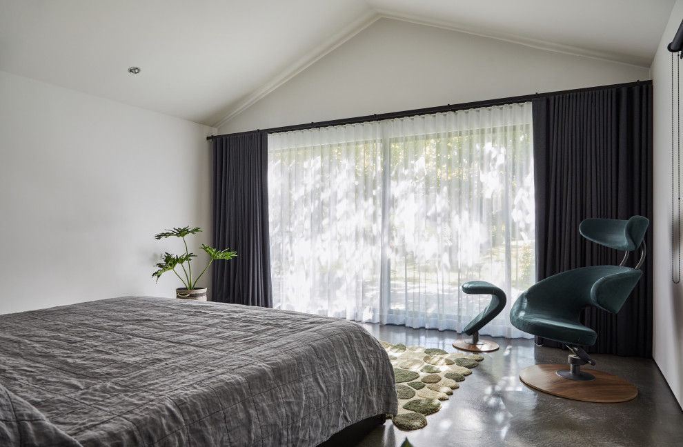 Large retro master bedroom in Los Angeles with white walls, concrete flooring, a standard fireplace, a plastered fireplace surround and grey floors.