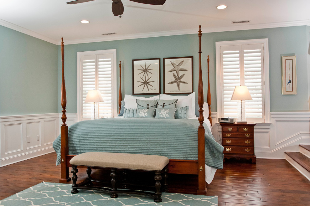 Modelo de dormitorio principal costero grande con paredes azules y suelo de madera oscura