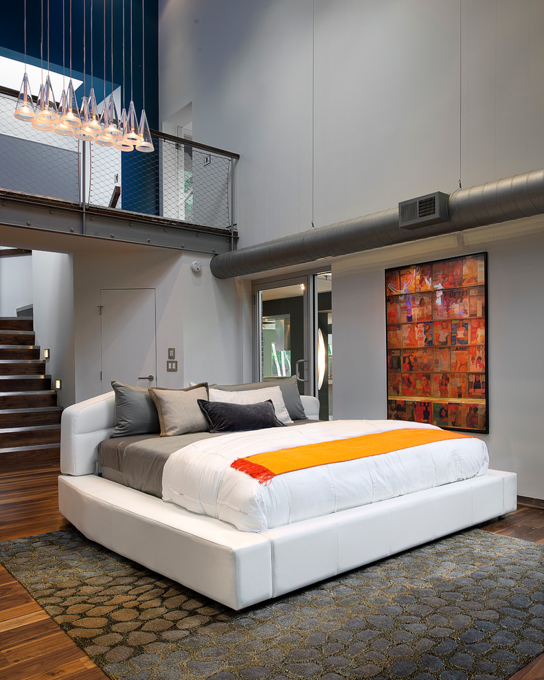 Bild på ett industriellt sovrum, med vita väggar och mörkt trägolv